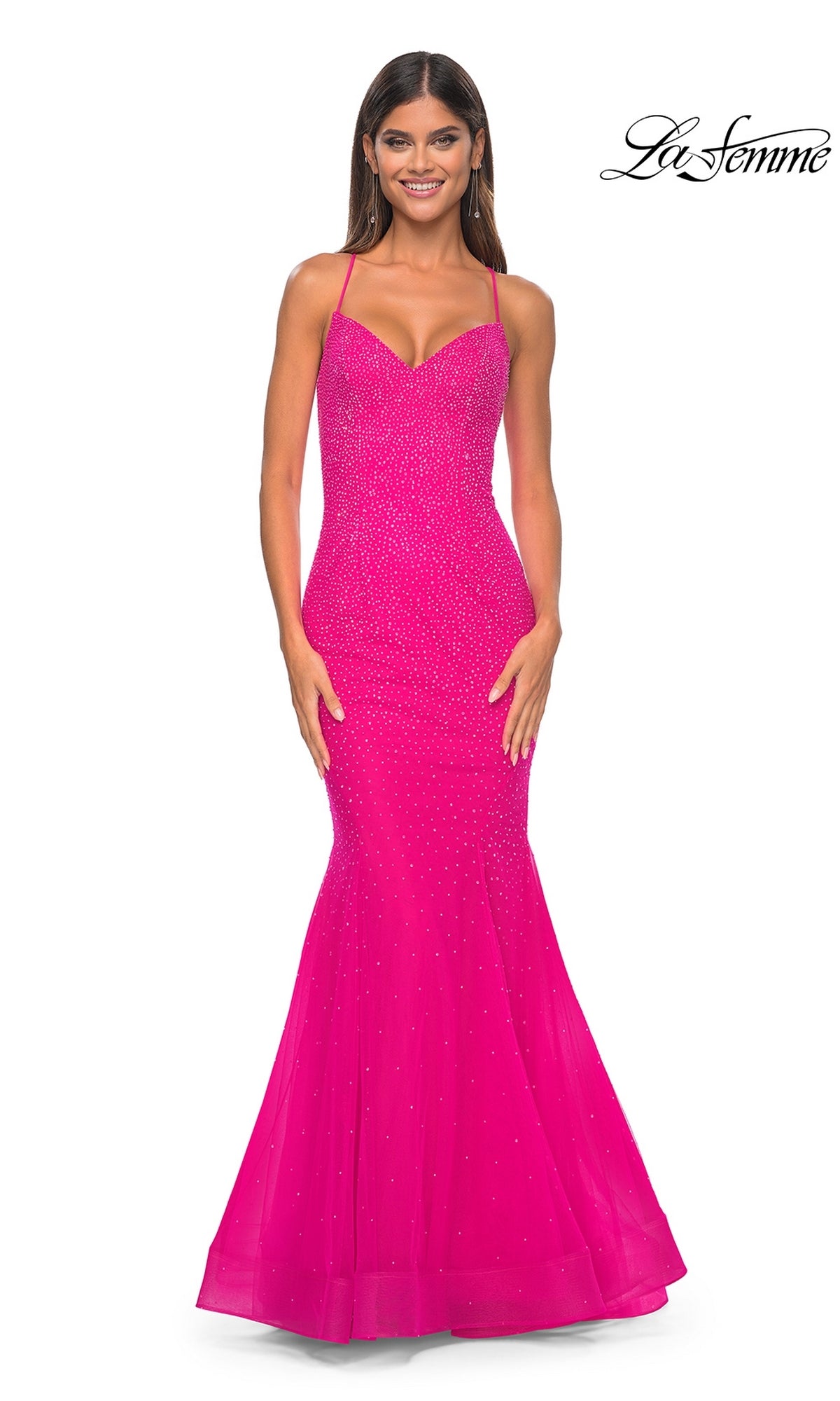 A woman smiles in the La Femme Embellished Long Mermaid Prom Dress 32273, a hot fuchsia, floor-length gown with thin straps and subtle sparkle. The La Femme logo appears in the top right corner.